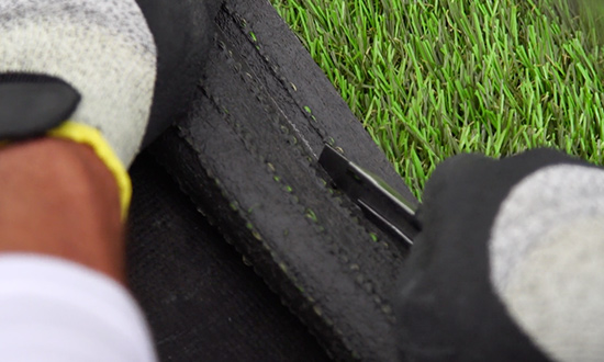 Cutting synthetic grass strips with a cutter